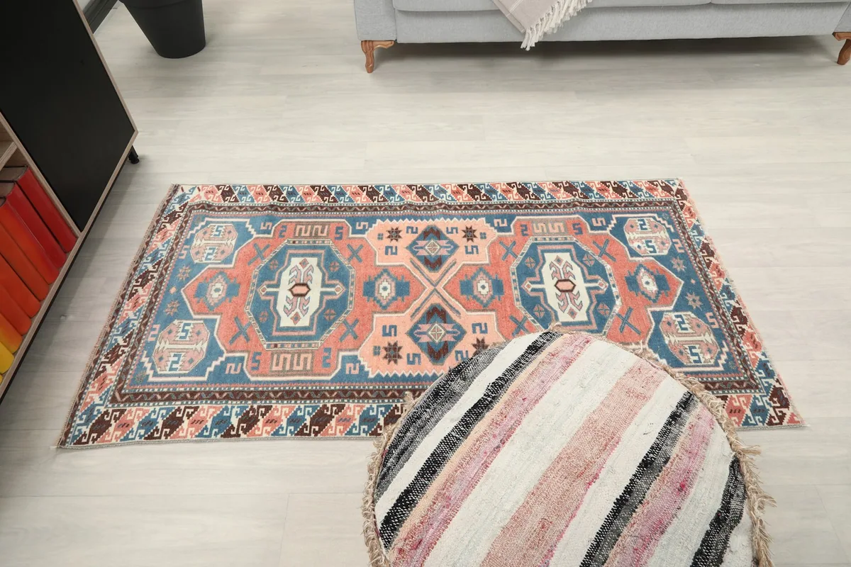 Anatolian rug in a room, viewed from above, with a striped ottoman in the foreground