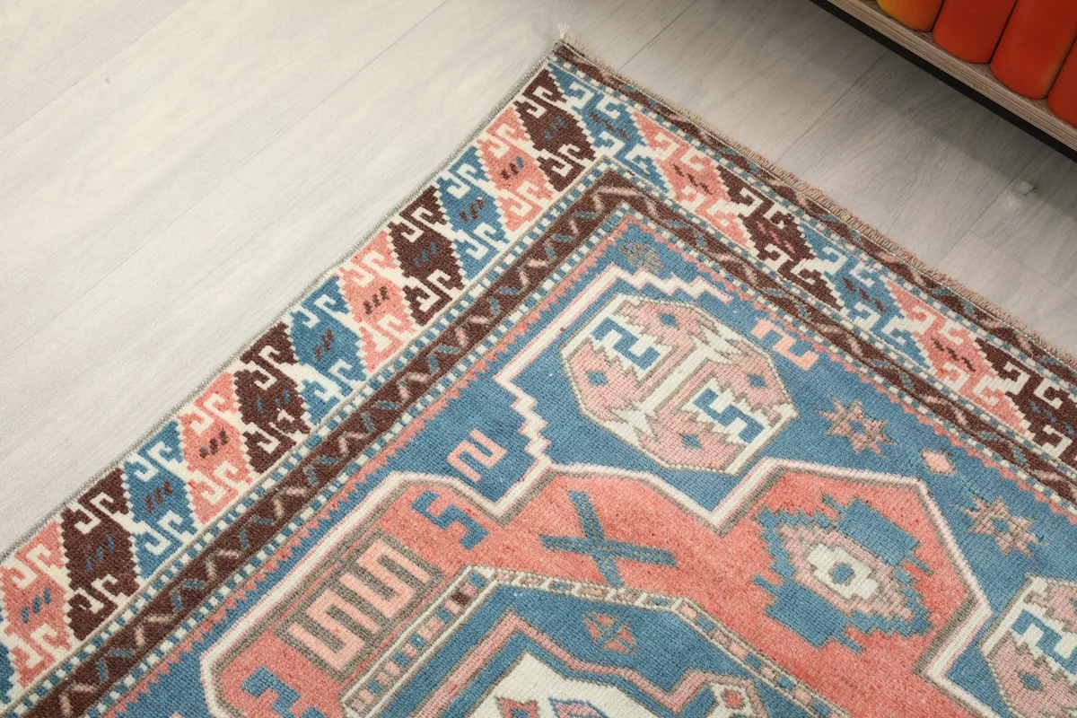Detail of the rug's corner and border, showcasing the brown, blue, and rust patterns