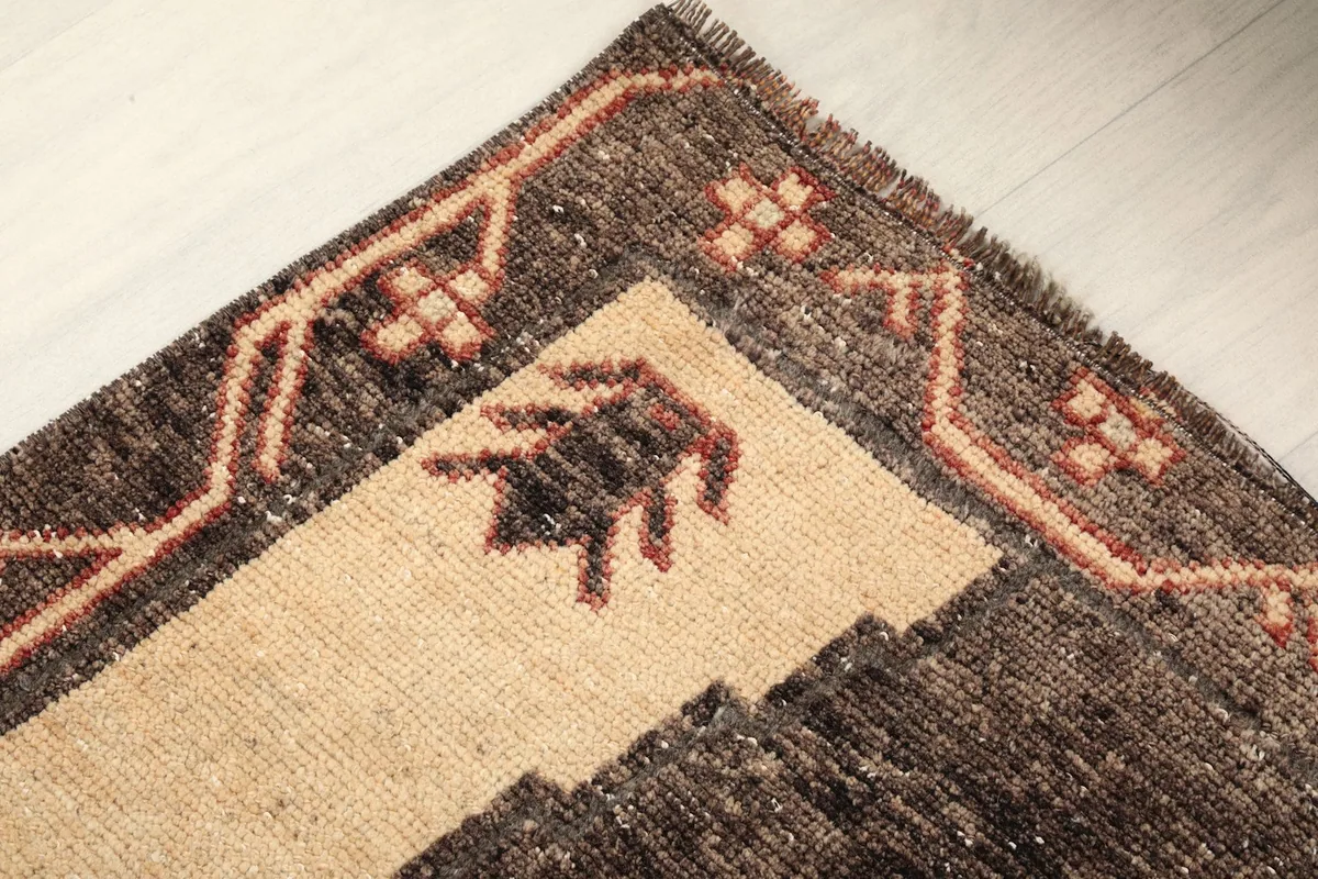 Close-up of the rug's end, showing fringe, border, and beige corner design