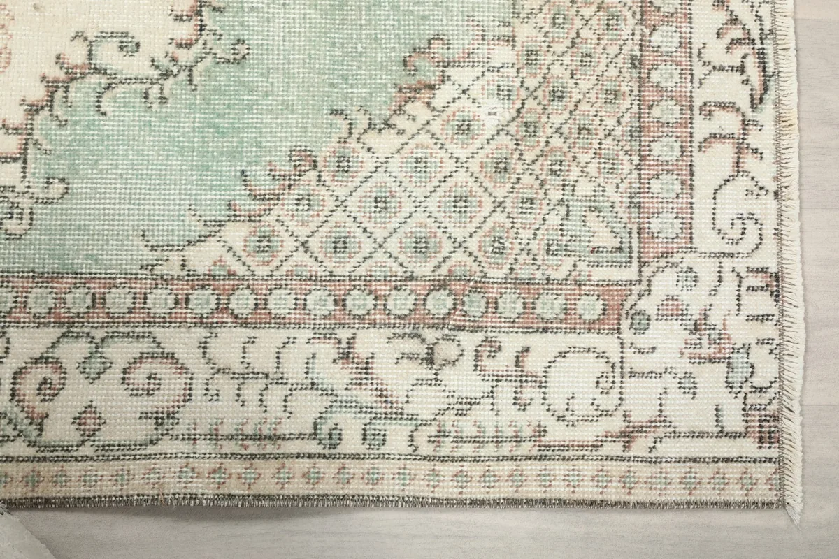 Detailed view of the rug's border and corner, highlighting geometric motifs and faded colors