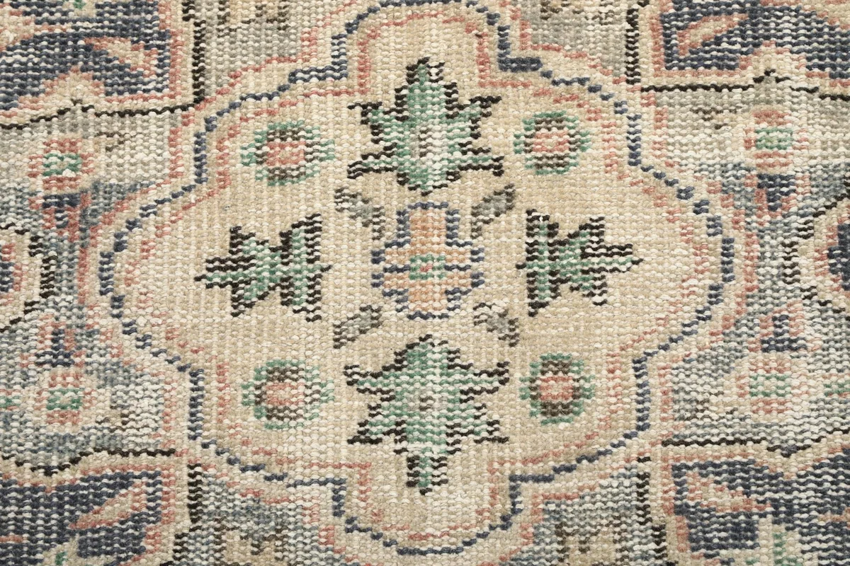 Close-up of the intricate wool pile texture and geometric patterns in ivory and green