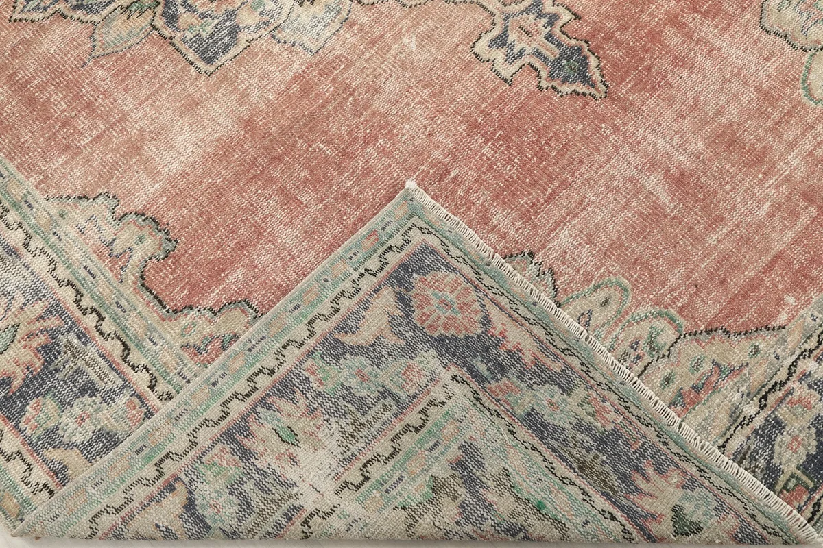 Folded corner of the rug revealing the thickness and the intricate border design