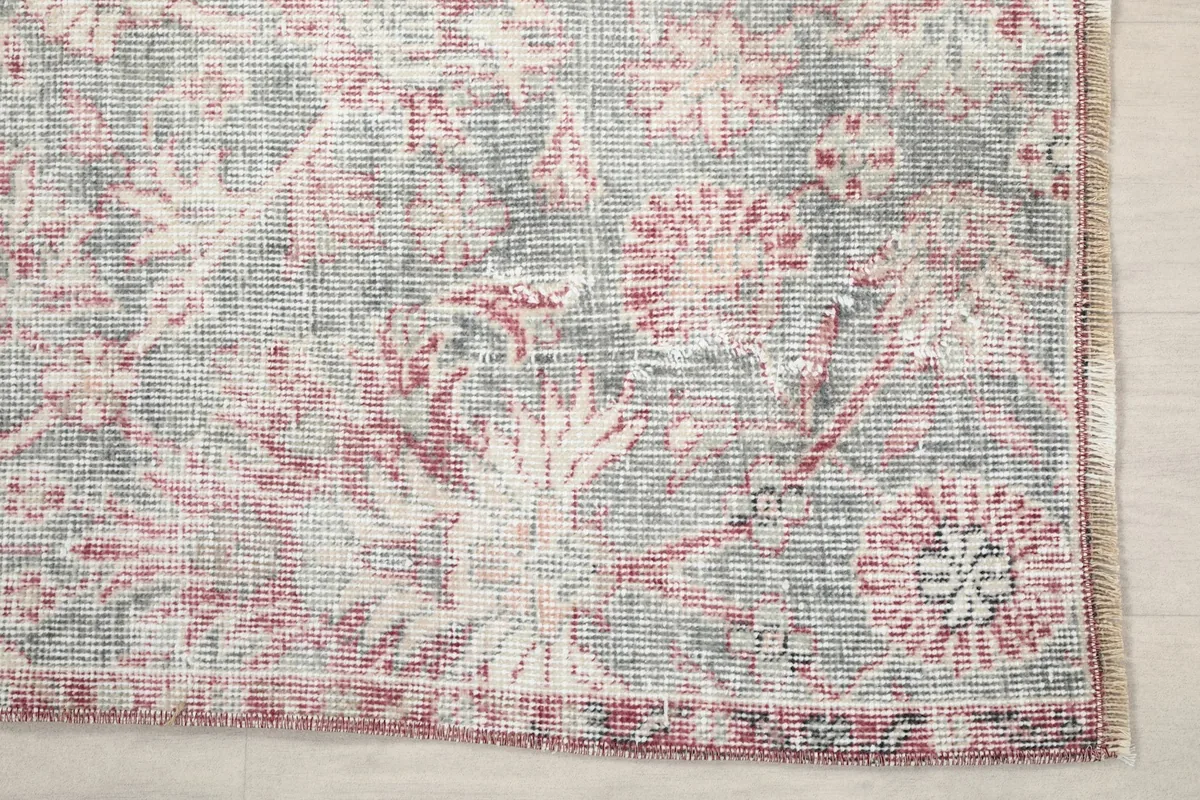 Detailed view of the rug's corner, showing the distressed rose and gray floral patterns