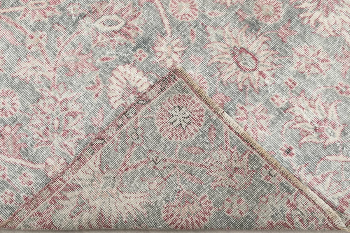 Corner of the rug folded back to reveal the cotton foundation and knotting