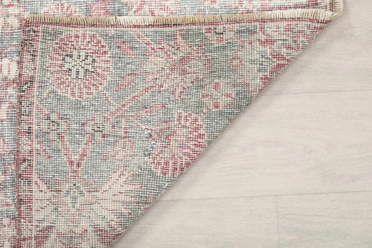 Another view of the rug's corner folded, showing the reverse side and fringe
