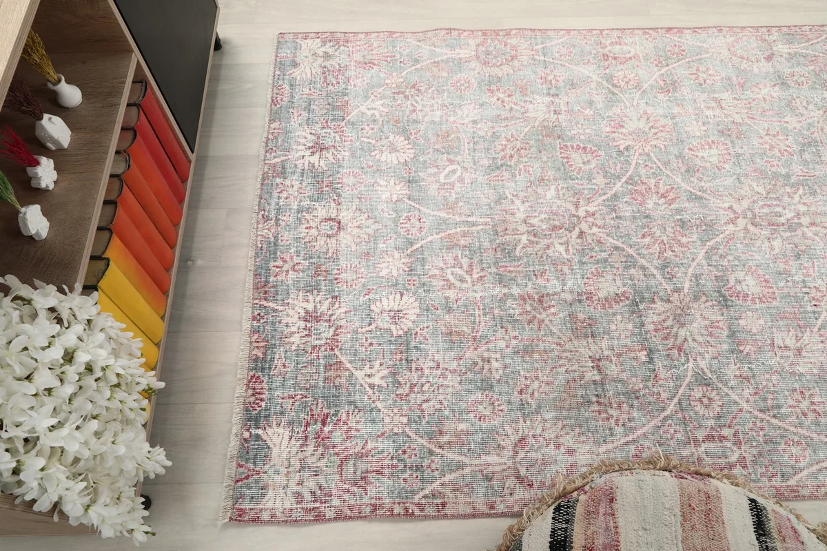 Elevated view of the rug on the floor, capturing the distressed gray and rose tones