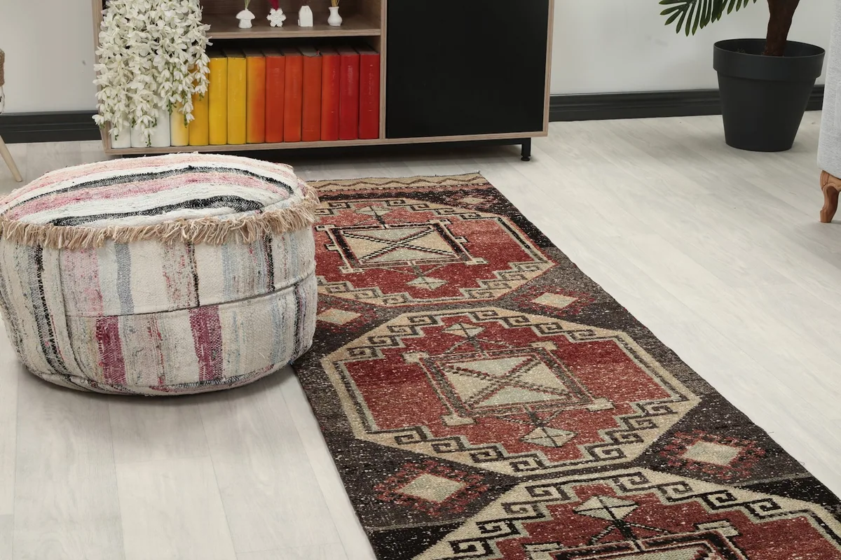 Close-up of the runner rug's pattern next to a striped ottoman, highlighting the rust and beige tones