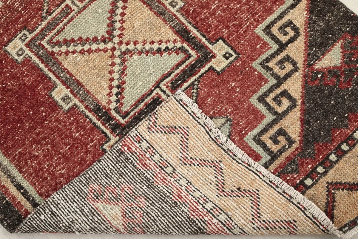 View of the rug's underside and corner, revealing the cotton foundation and hand-knotted construction