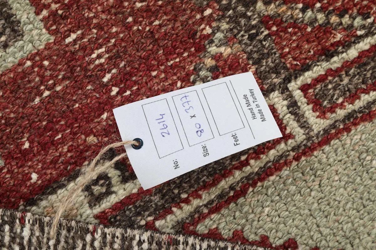 Close-up of the product tag attached to the rug, displaying item number, size in cm and feet, and origin