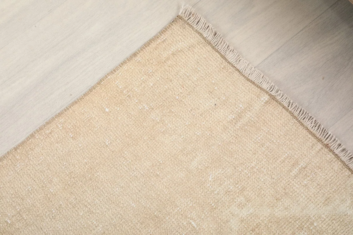 Corner view of the tan runner rug, highlighting the soft fringe and wool texture