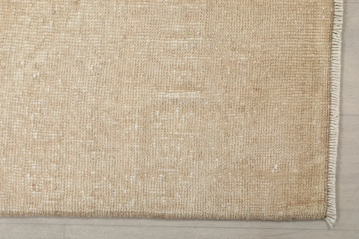Detailed overhead view of the hand-knotted wool pile and subtle tan color variation