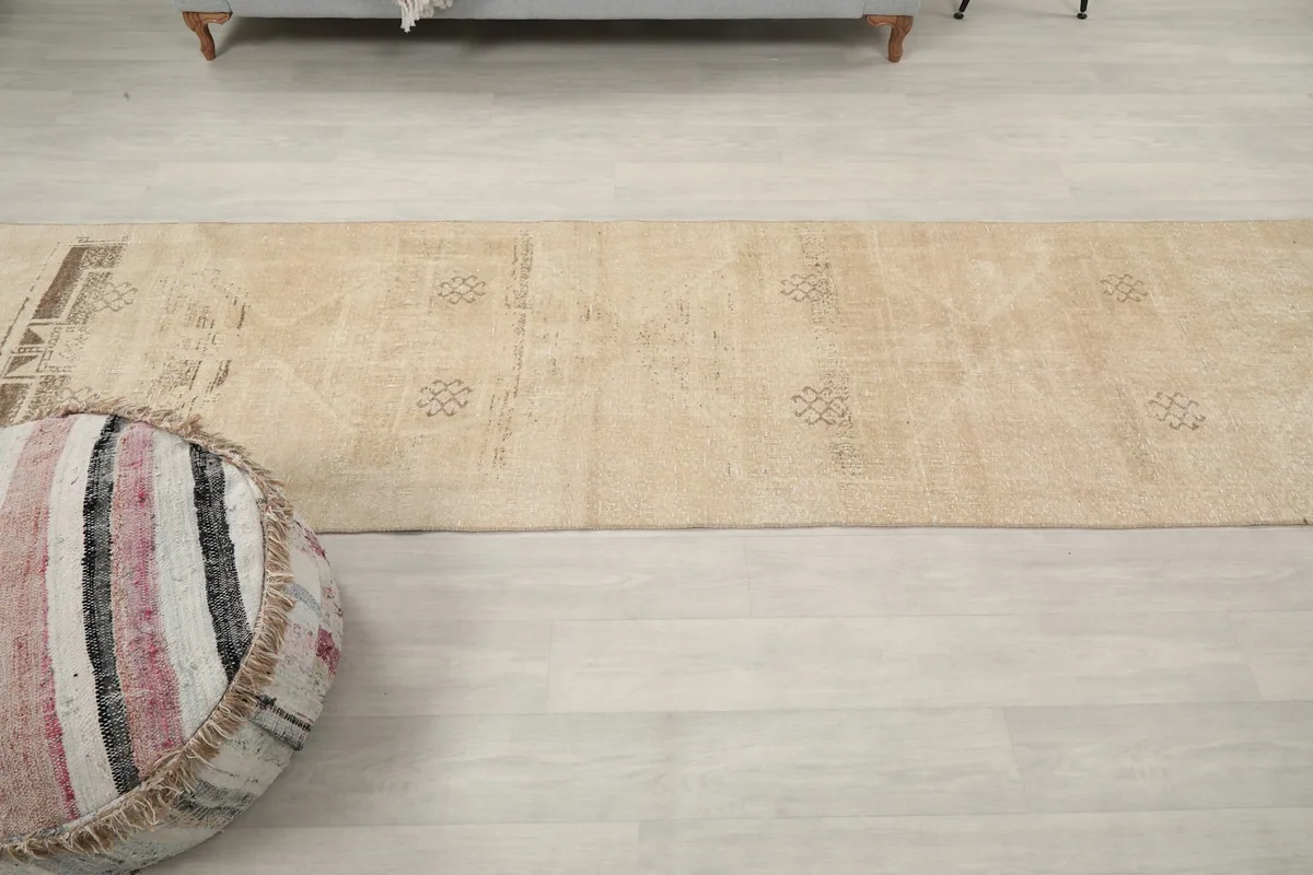 Overhead view showing the full length and various geometric motifs of the tan runner rug