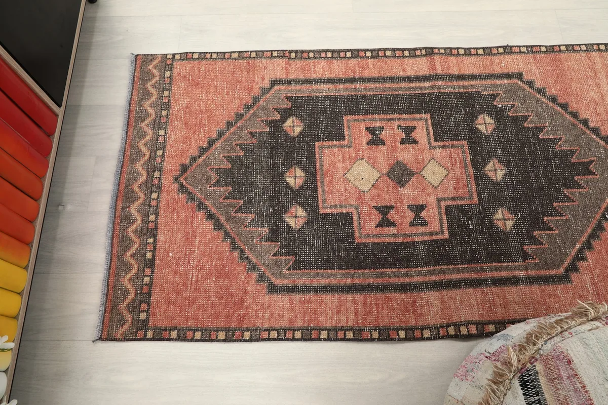 Angled overhead shot focusing on one end of the rust and charcoal geometric runner rug.