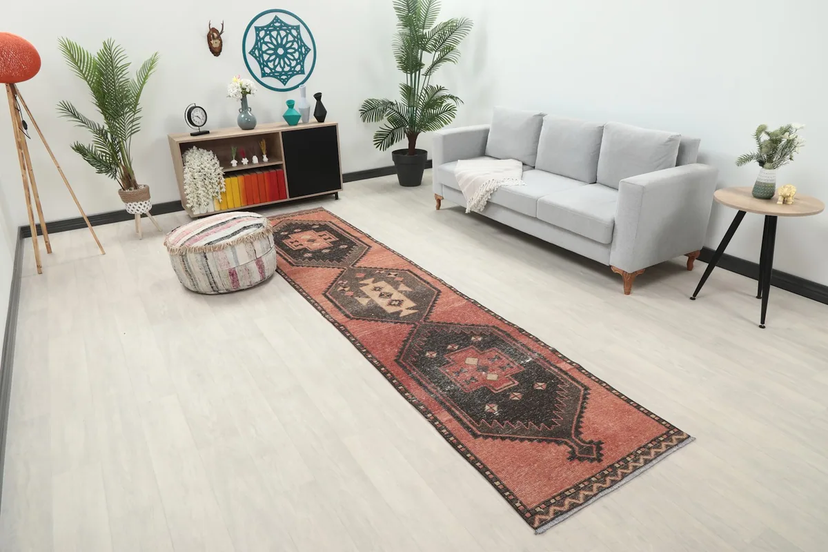 Angled view of the rust geometric runner rug in a room, highlighting its placement next to a sofa.