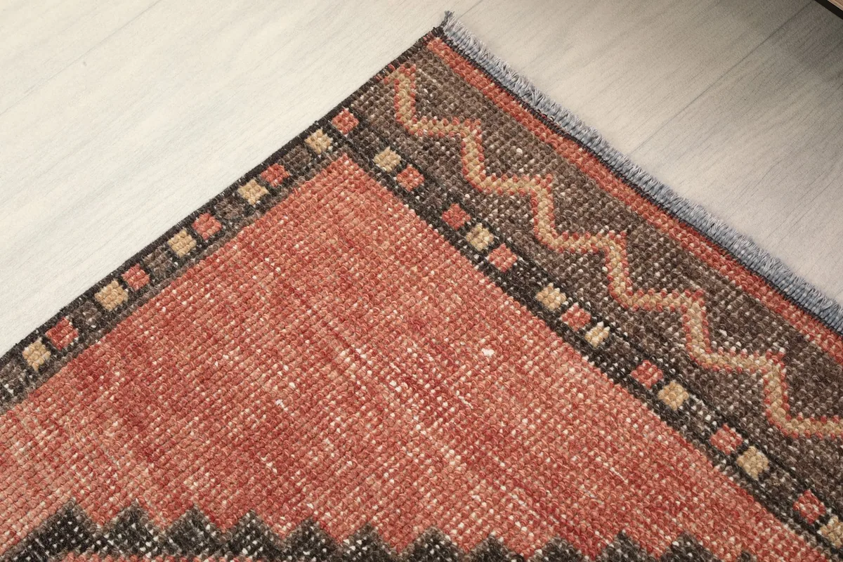 Detail of the outer border and edge of the rug, showcasing the subtle color variations and wear.