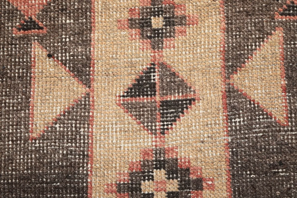 Extreme close-up showing the low wool pile and intricate knotting of the vintage runner rug.