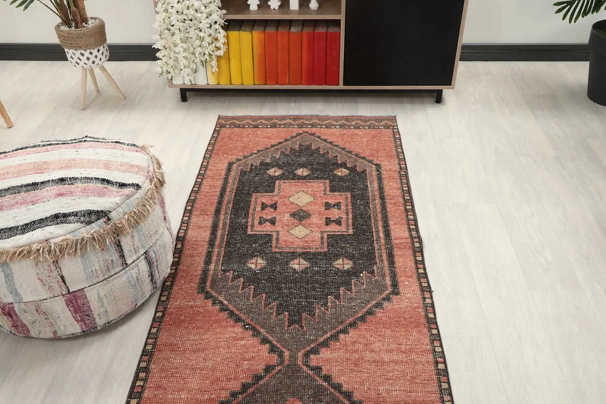 Overhead view of a section of the rust and charcoal runner rug in a room, showing its pattern.
