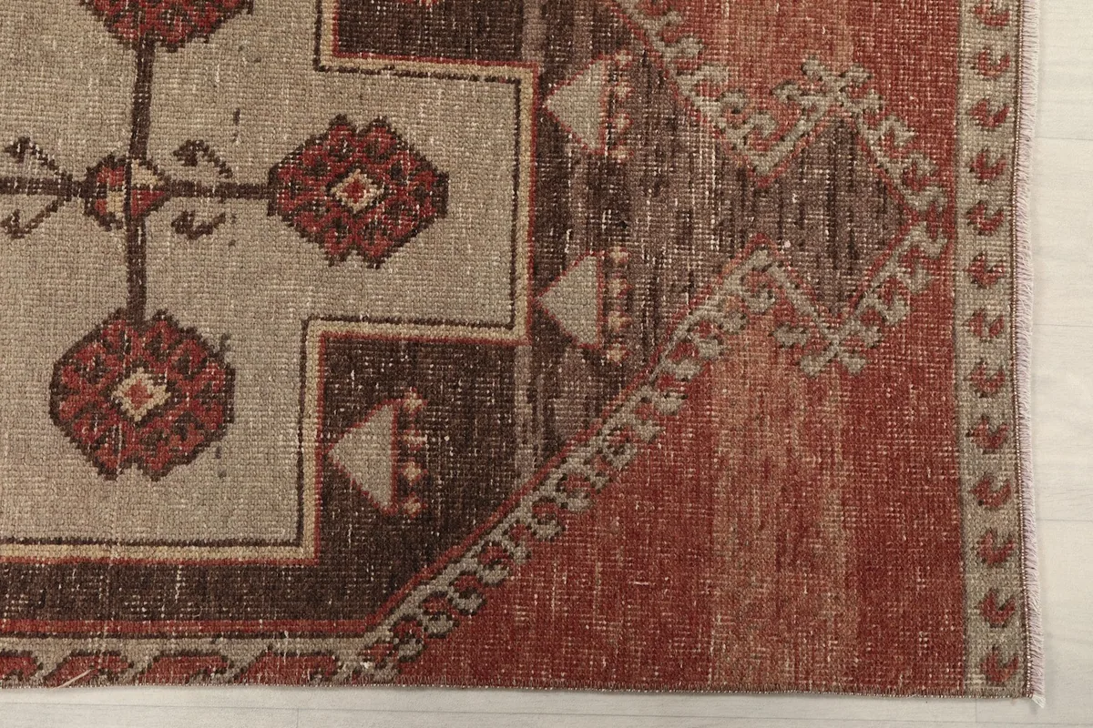 Detailed view of the rug's border and a section of the main rust field with visible wear