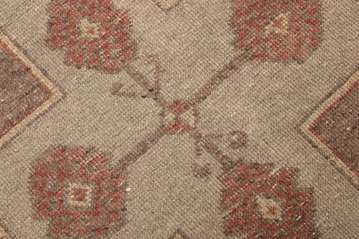 Extreme close-up of the hand-knotted wool pile and the intricate floral-like details within the geometric pattern