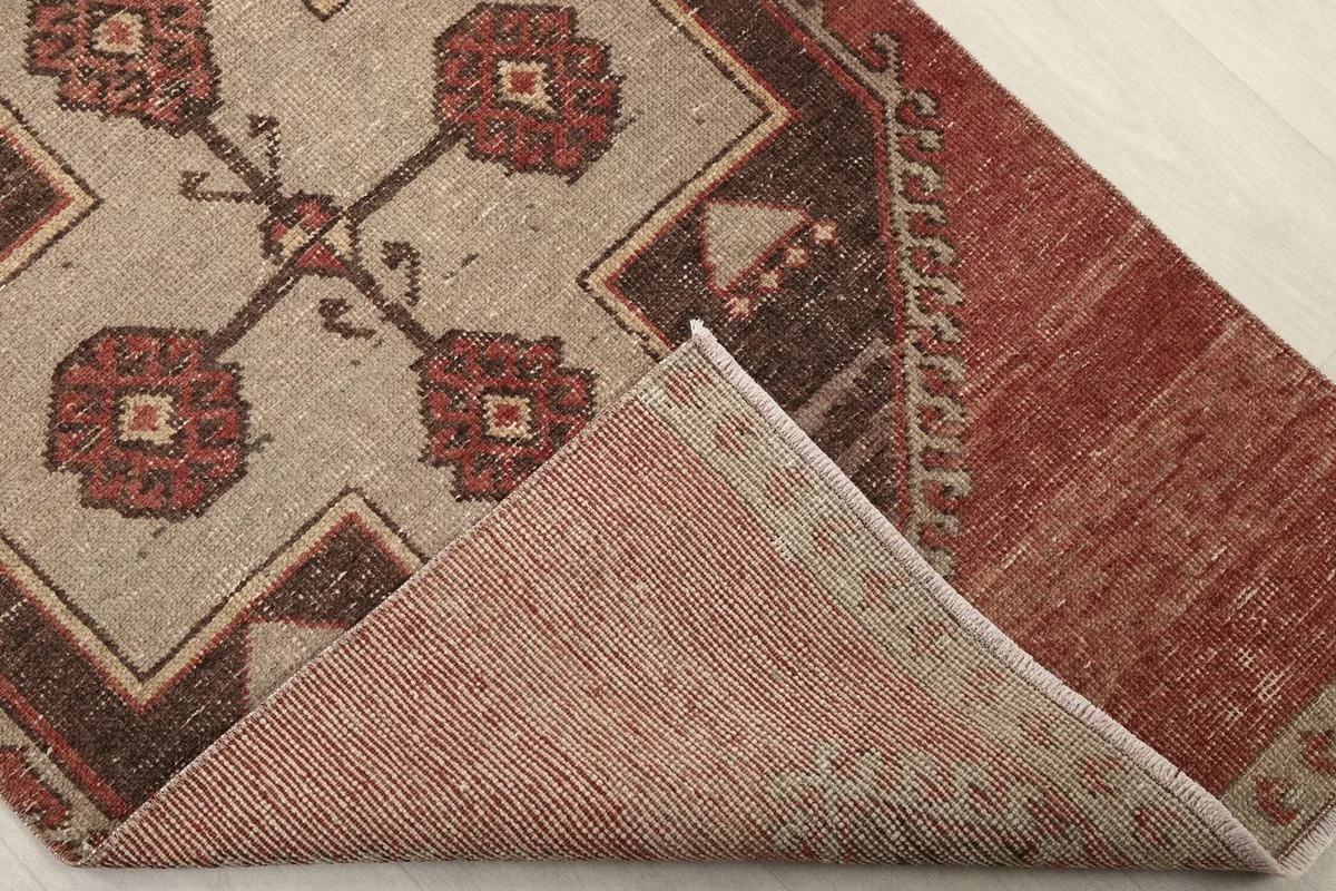 Corner of the rug folded back to reveal the cotton foundation and hand-knotted reverse side