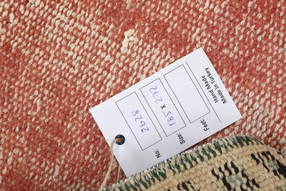 Close-up of the rug's back with a tag showing size 185x272 cm and origin