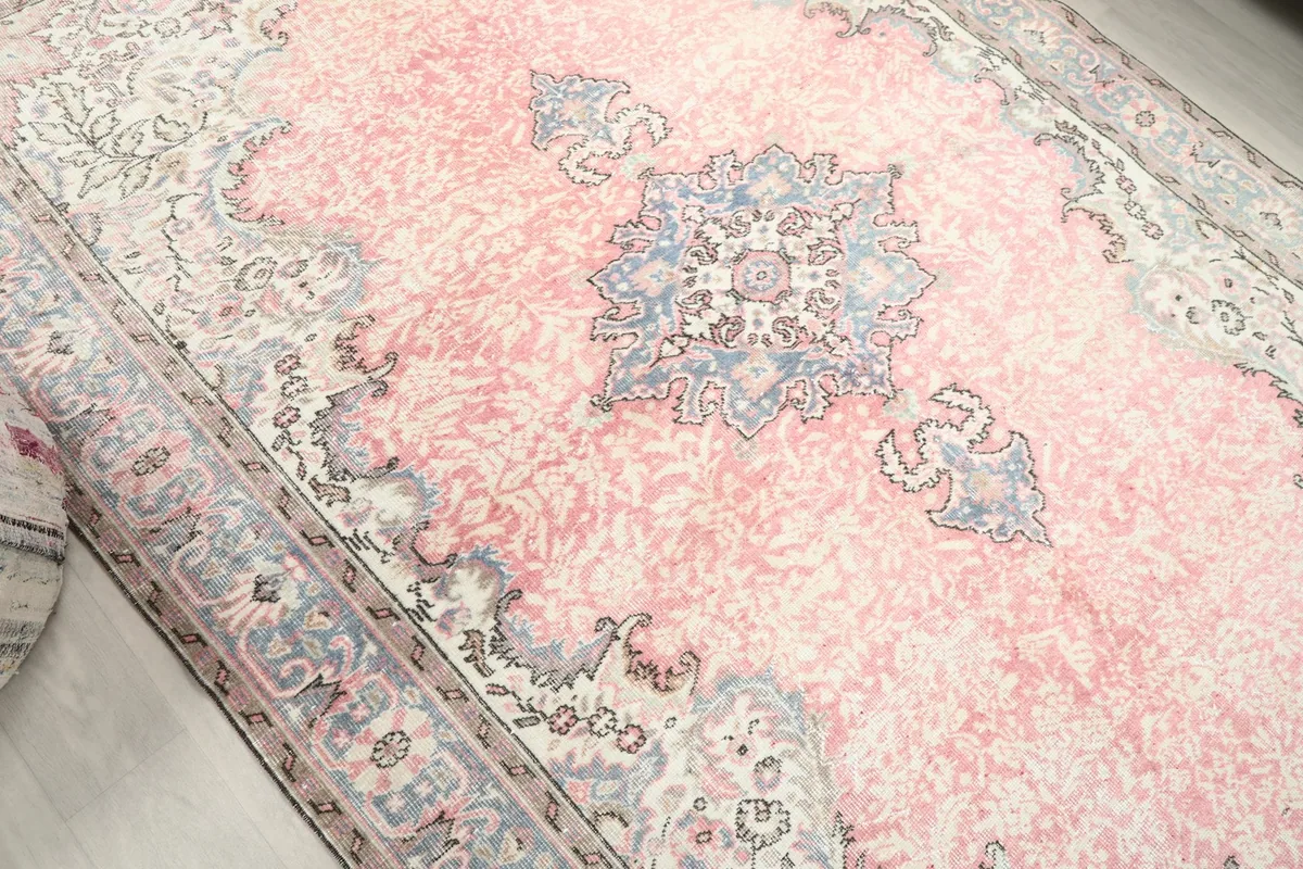 Overhead angle showcasing the central blue medallion and the faded rose field of the area rug