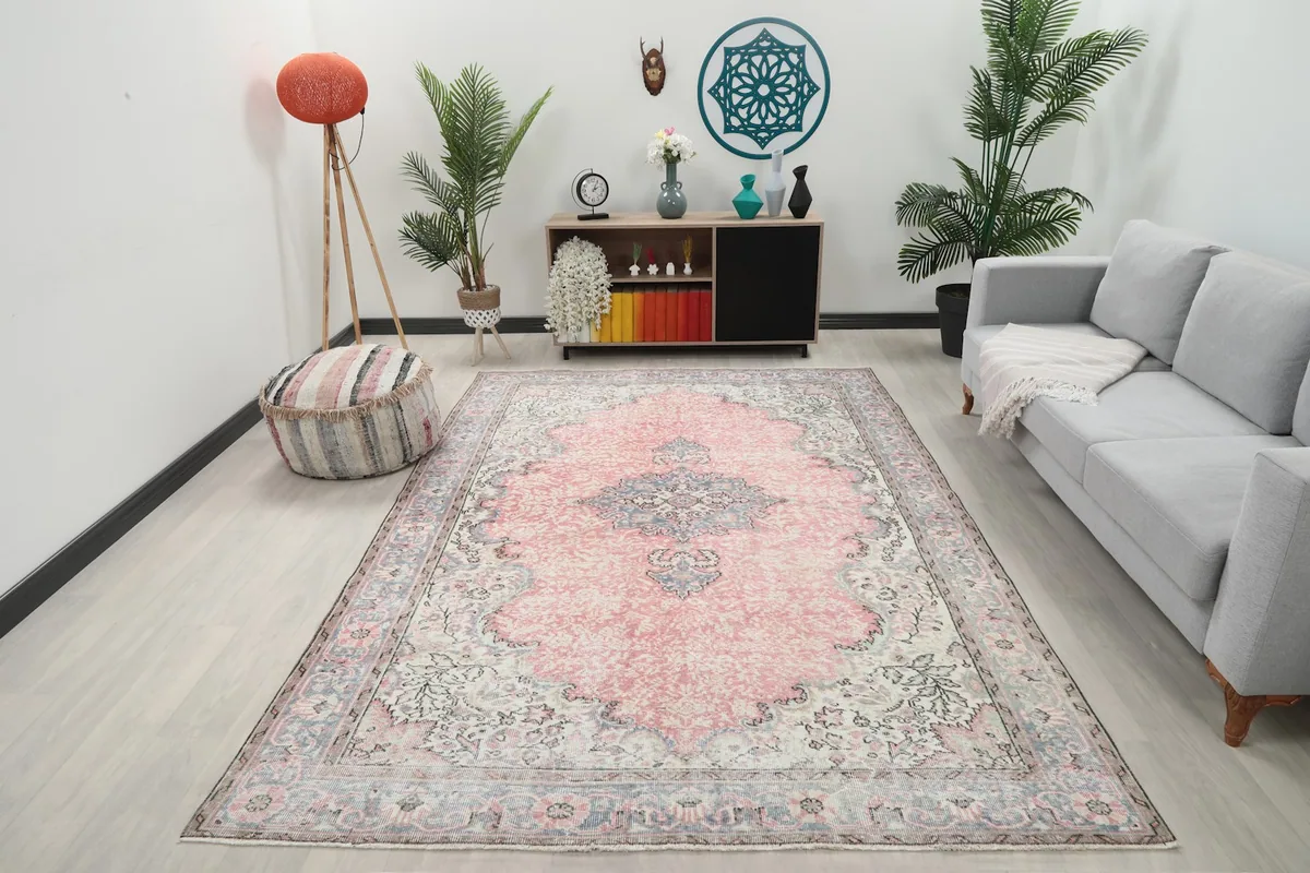 Vintage area rug displayed in a bright living room setting with a gray sofa and plants