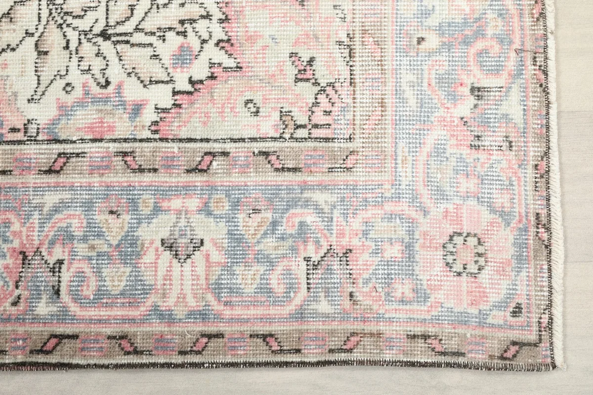 Detailed view of the blue and ivory border with floral and geometric motifs on the vintage rug