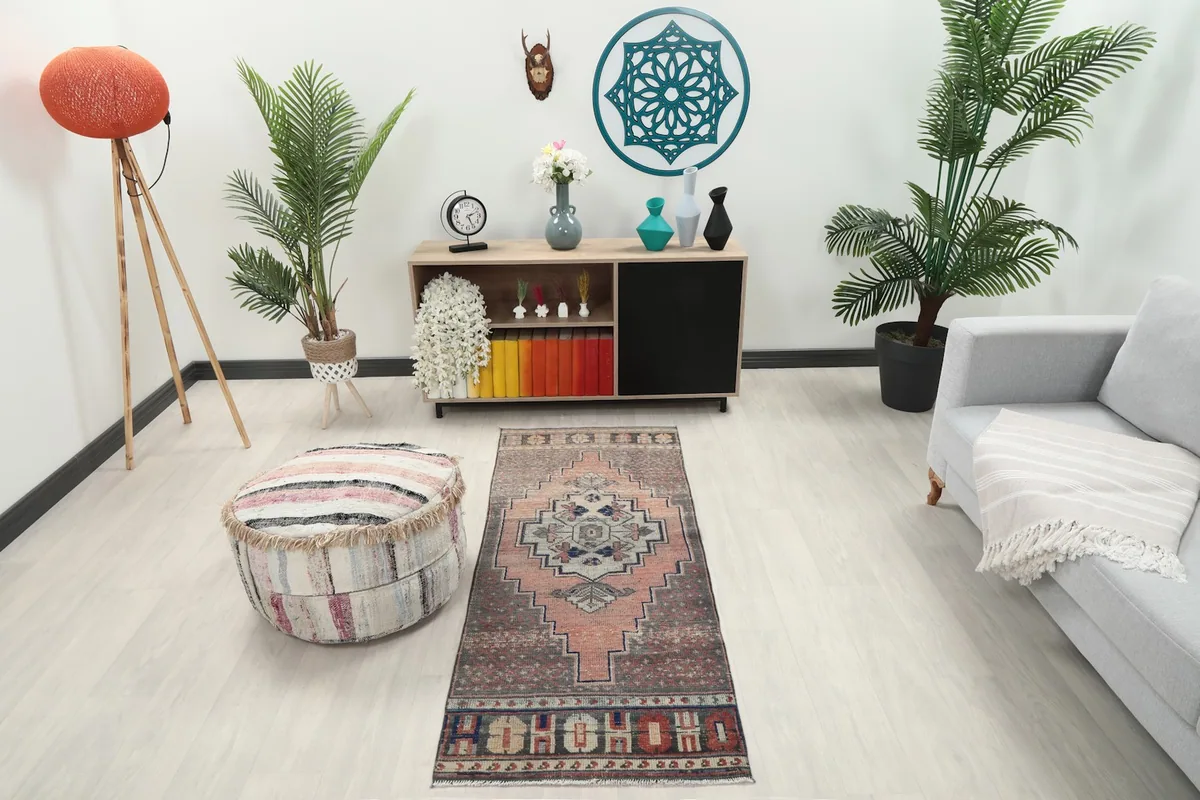 Vintage runner rug in a room setting with a sofa and ottoman, showing its scale