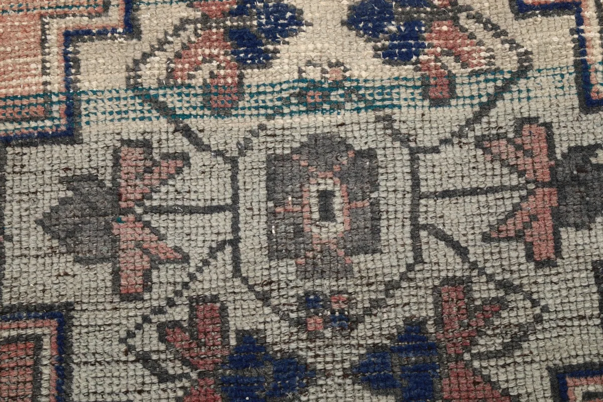 Macro close-up showing the hand-knotted wool pile and intricate detail of the central motif
