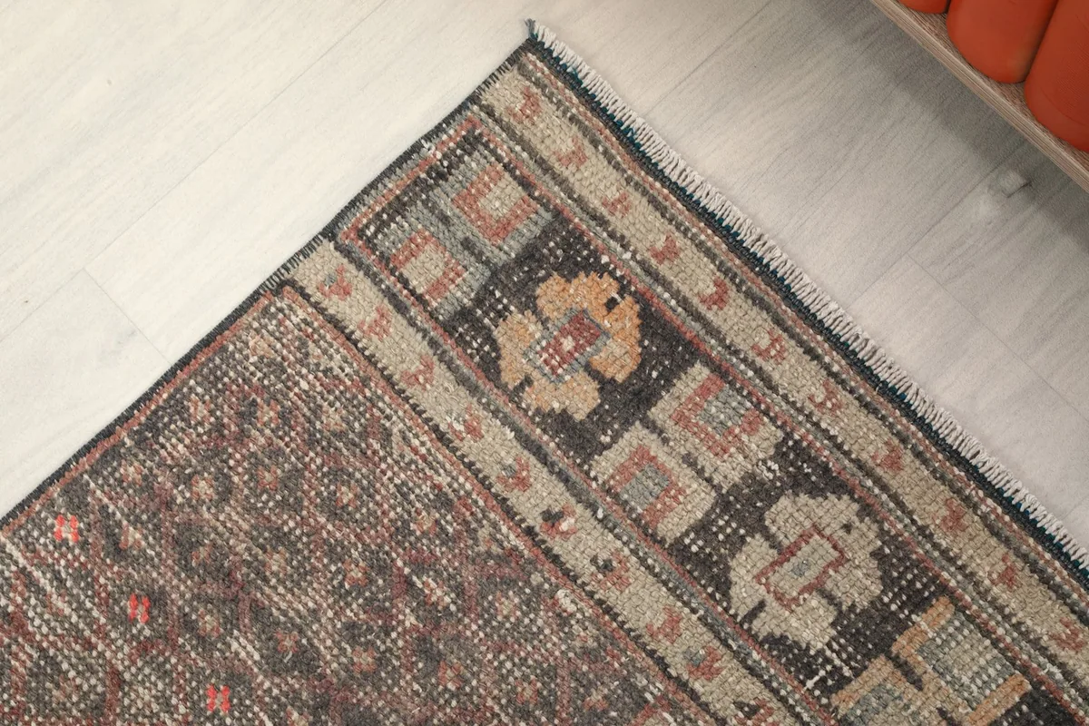 Close-up of the rug's bottom border and corner, highlighting the patterns and fringe