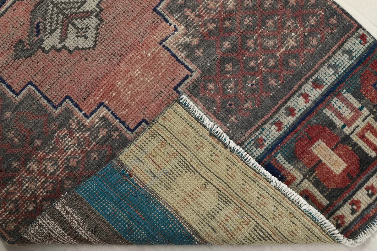 Corner of the rug folded to show the cotton foundation and reverse side of the knots