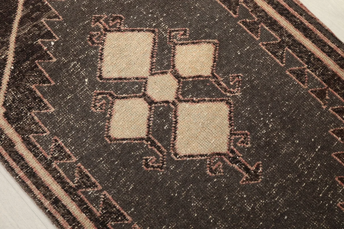 Close-up of the central geometric motif within a charcoal medallion with beige details