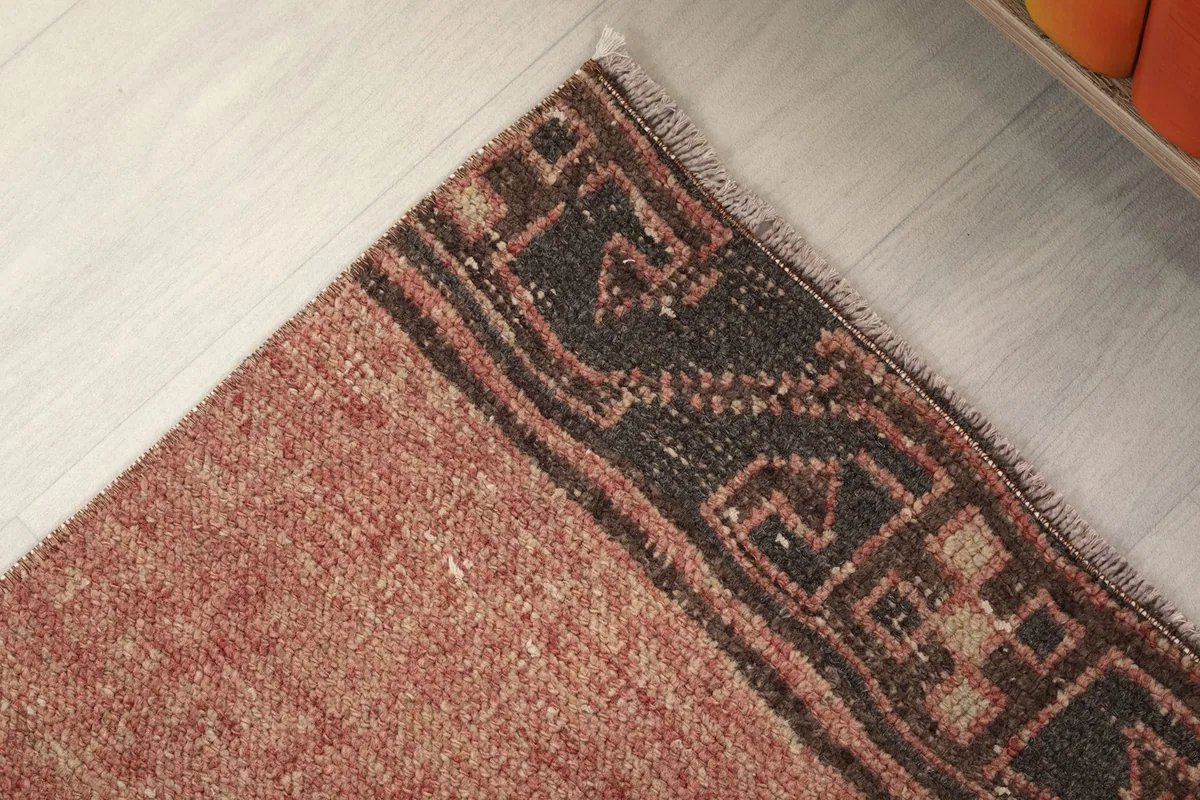 Detail of the rug's border and corner, showing faded colors and tribal motifs
