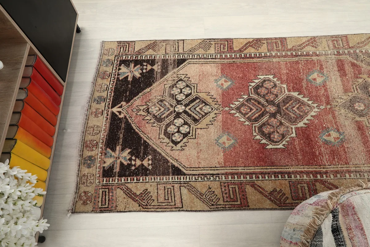 Upper section of the runner rug from an angle, showcasing the darker brown and black motifs
