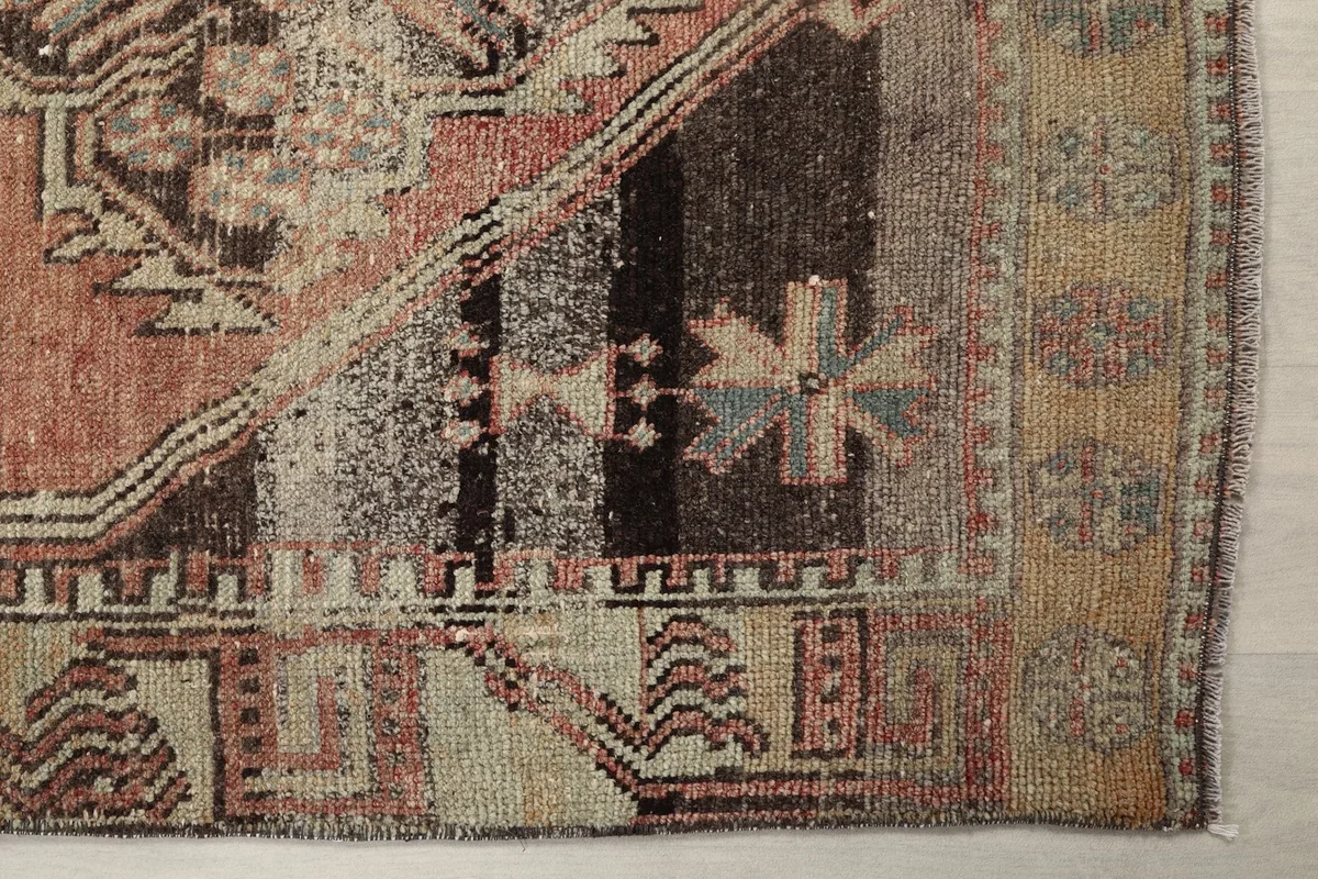 Detailed view of the intricate geometric patterns and color variations in the rug's border and field