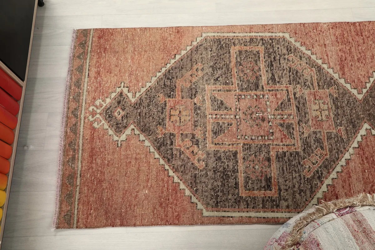 Angled view of the rust and brown runner rug in a room, capturing its full width