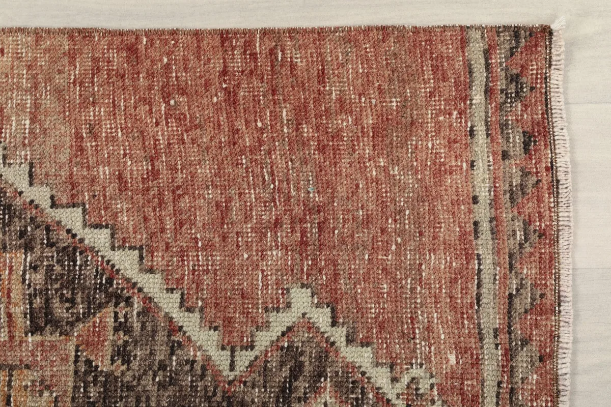 Close-up detail of the rust field and part of the brown geometric pattern on the rug
