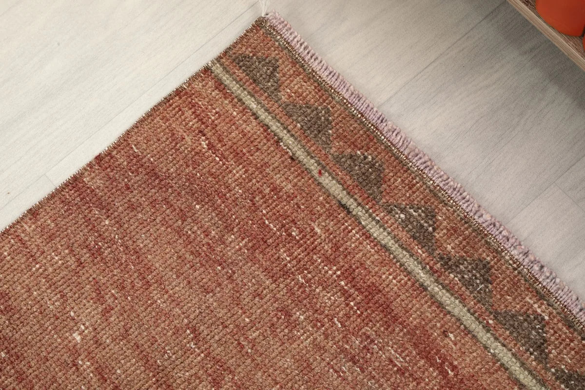Detail of the edge of the rust runner rug, showing the subtle border and fringe