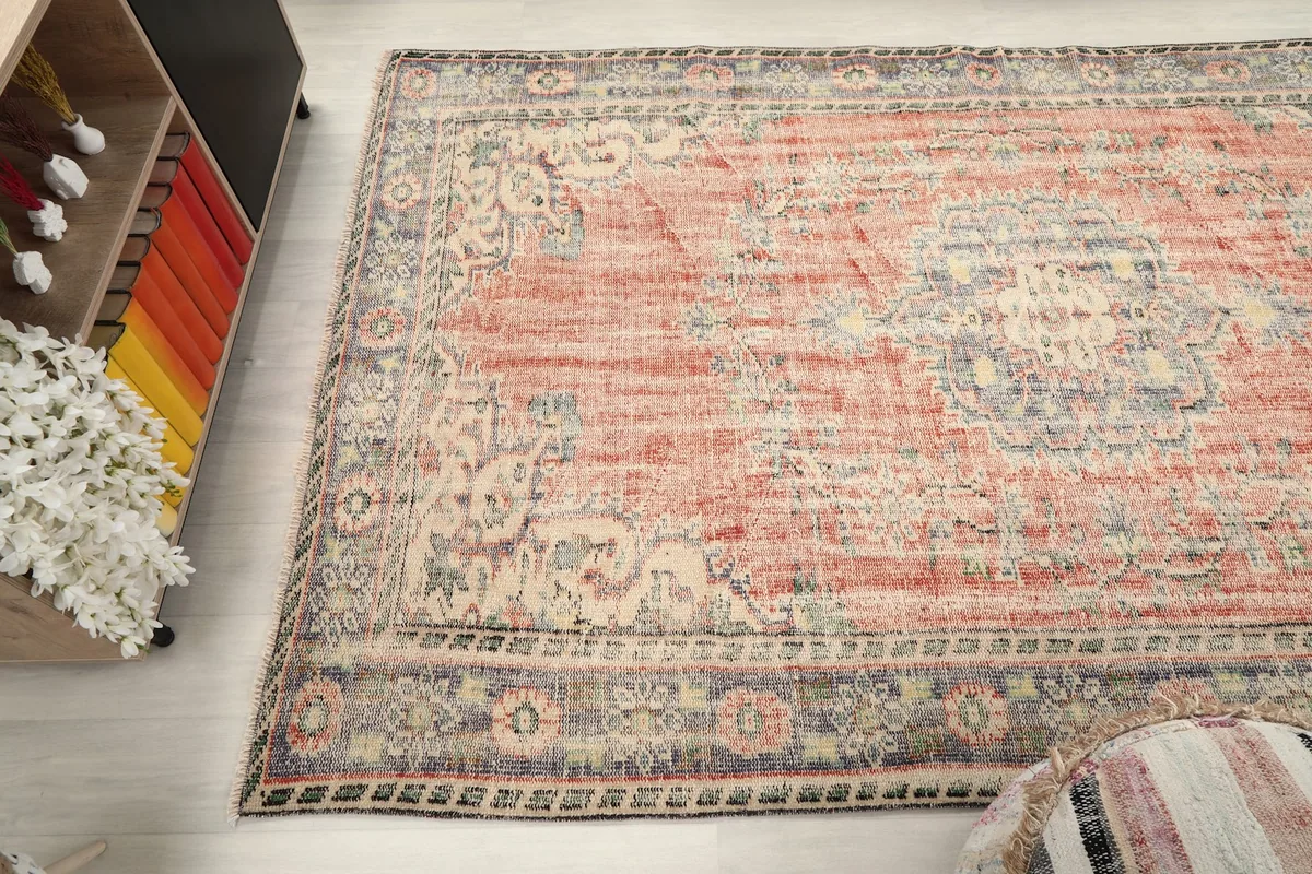 Wide shot of the vintage area rug placed in a living space, demonstrating its scale and color palette