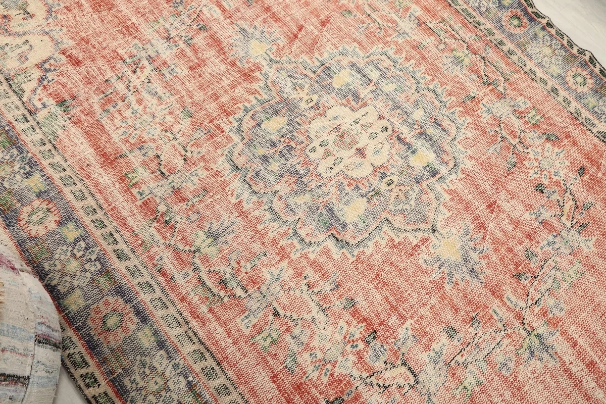 Angled close-up showing the central blue medallion and faded rose field with textural variations