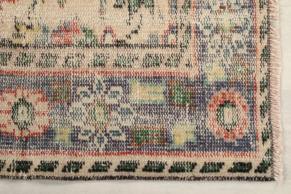 Detailed view of the rug's blue and ivory border with floral and geometric patterns