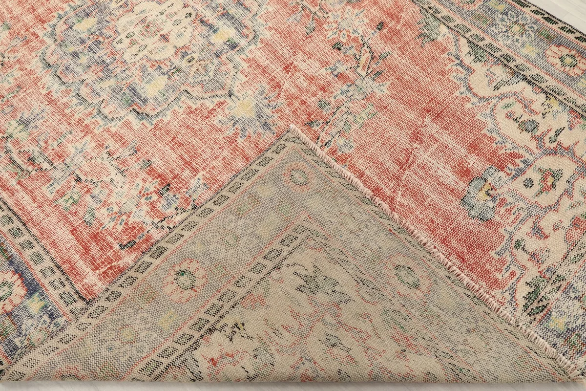 View of the rug's underside and folded corner, revealing the cotton foundation and hand-knotted construction
