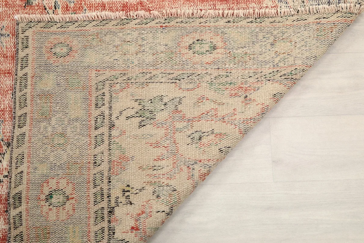 Close-up of a folded corner, showing the tightly woven cotton foundation and reverse side of the rug