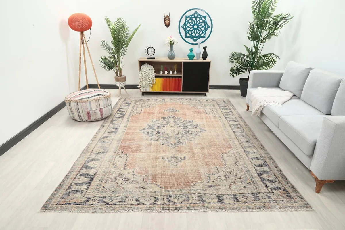Rust and blue vintage rug in a modern living room setting with a gray sofa and wooden cabinet.