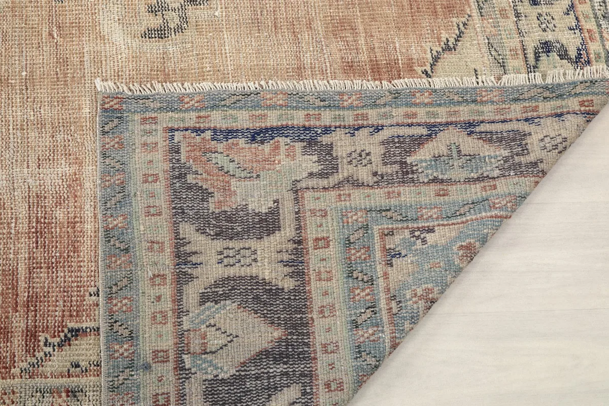 Another view of the folded rug corner, showing the foundation and the base of the fringe.