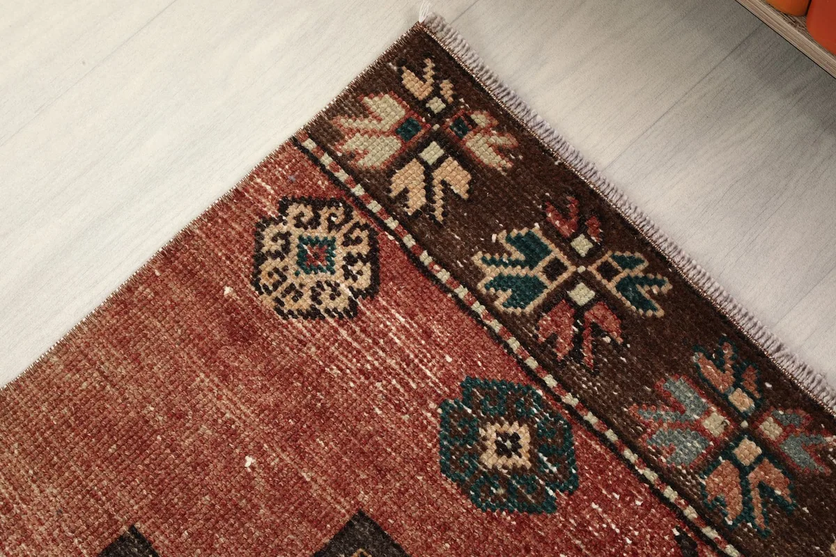 Detail of the rug's end border featuring small floral patterns and a distinct charcoal color