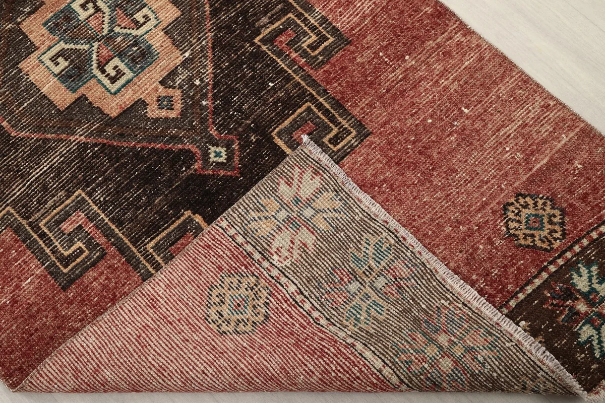 Corner of the rug folded back to show the cotton foundation and reverse side of the hand-knotting