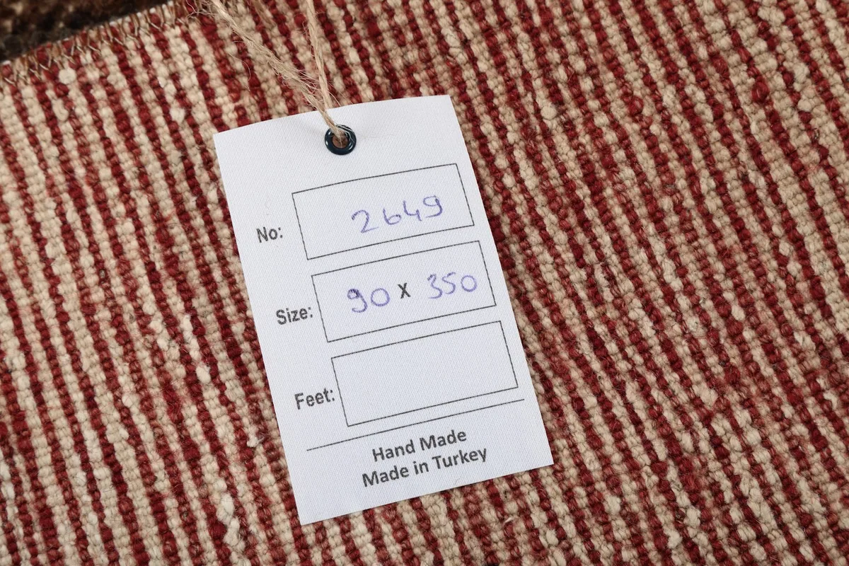 Close-up of the hand-made in Turkey tag attached to the rug's back, showing size in cm