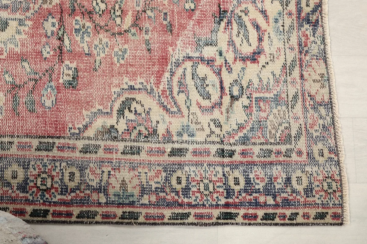 Close-up of the rug's border with blue, ivory, and rose tones